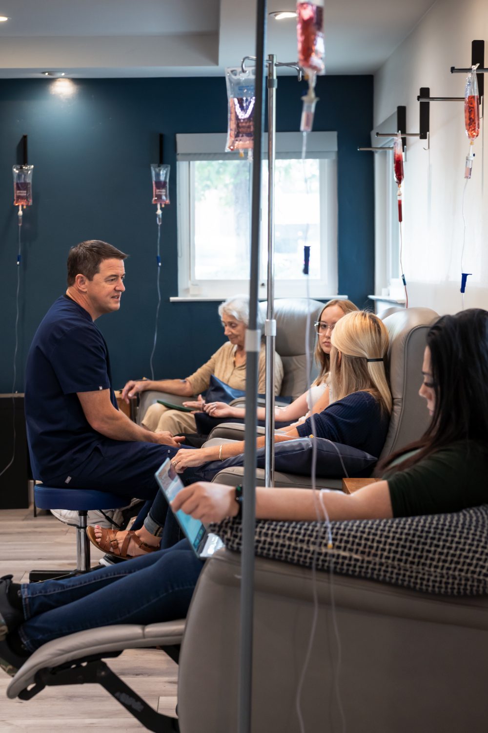 Patients resting in the YNC IV room while a team member checks a line